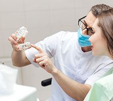 Dentist showing female patient model of implants