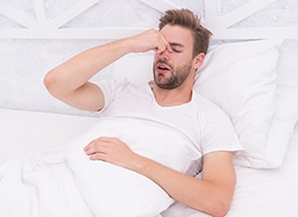 Exhausted man, struggling with symptoms of sleep apnea