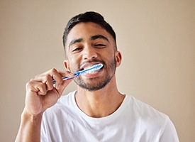Man brushing teeth with tan background