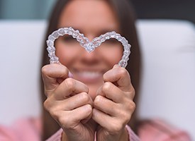 Woman holding clear aligners in a heart shape