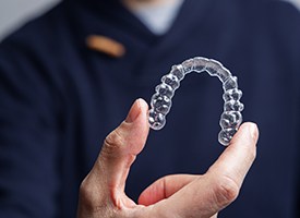 Man in navy scrubs holding Invisalign tray