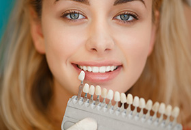 Woman's smile compared with tooth color shade chart