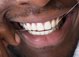Closeup of patient flossing his dental implants in Pittsburgh