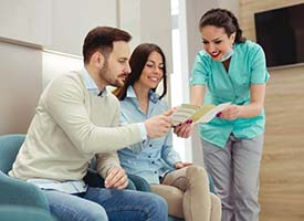 dental team member explaining the cost of emergency dentistry in Pittsburgh to two patients