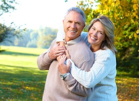 Older couple with dental implants in Pittsburgh smiling and hugging