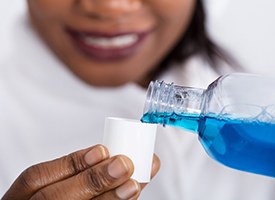Woman using mouthwash to clean her dental implants in Pittsburgh