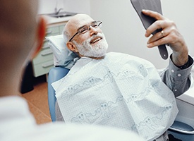 Older man completing a checkup with an implant dentist in Pittsburgh