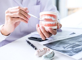 Implant dentist holding model explaining cost of dental implants in Pittsburgh