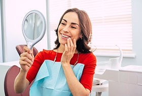 Woman with Invisalign in Pittsburgh smiling into mirror