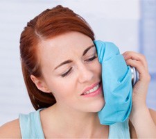 Woman using ice pack on cheek