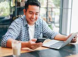 person sitting at a coffee chop and working on their phone and laptop