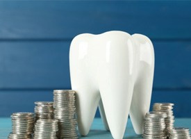 A large model tooth surrounded by silver coins