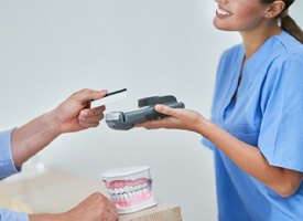 A man paying the cost of veneers electronically