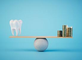 a tooth and coins balancing on a scale