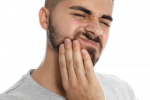 Bearded man in gray shirt rubbing his jaw