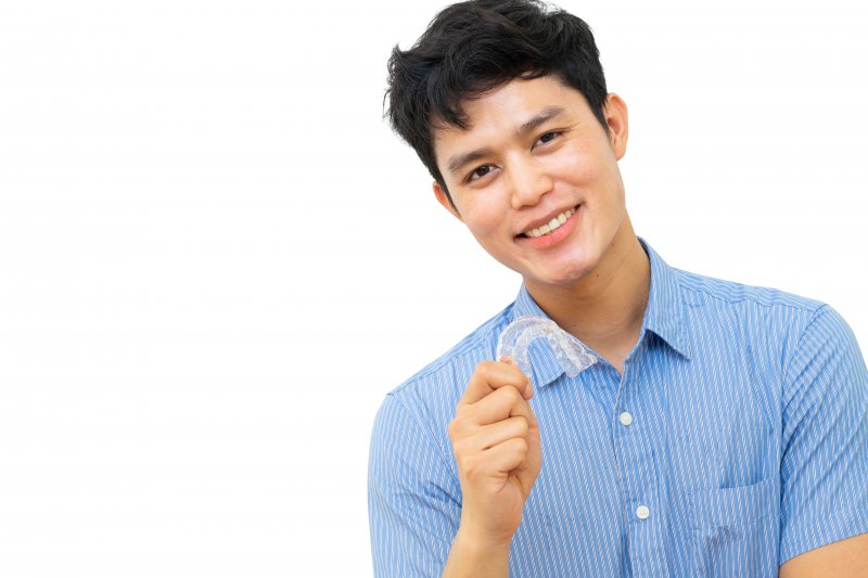 person holding Invisalign and smiling