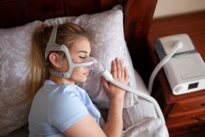 Woman sleeping while undergoing an at-home sleep apnea test.