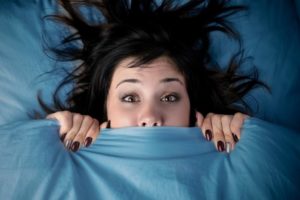 Woman lying in bed feeling anxious.