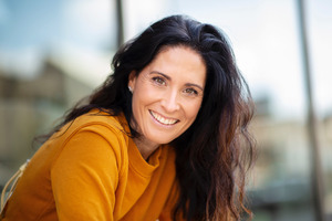 Woman in orange shirt sitting and smiling