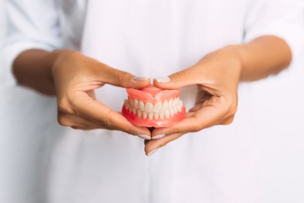 A woman holding a pair of dentures