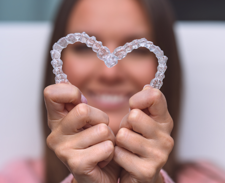 Woman holding clear aligners in heart shape