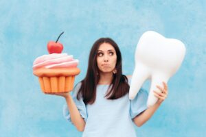 woman holding large cupcake and oversized tooth